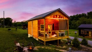A wooden cabin with a porch, a fire pit, and a small outdoor seating area.