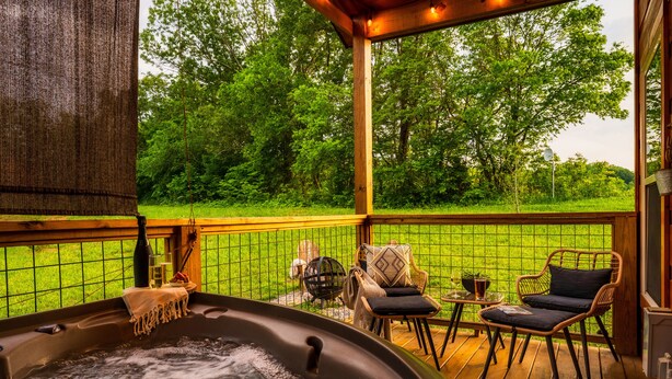 A hot tub on a wooden deck with a view of a green landscape.