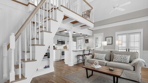 Amplia sala de estar con escalera, cocina y zona de estar con sofá y mesa de centro.