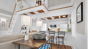 Una cocina moderna con armarios blancos, encimera de madera y microondas integrado.