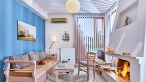 Una sala de estar moderna con sofá, mesa de madera, una silla, chimenea y un ventanal con cortinas.