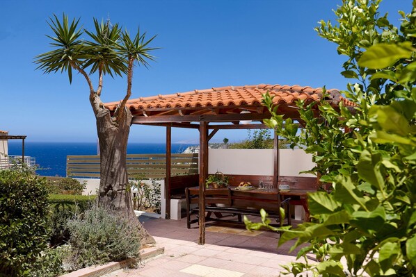 A patio with a pergola, a dining table, and chairs.