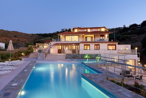 Une maison à deux étages dotée d’une piscine, d’un espace salon extérieur et d’un escalier menant à l’étage supérieur.