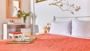 Una camera da letto ordinata con un letto, un comodino, una lampada e uno specchio.