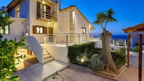Una casa a due piani con un balcone, una scala e vista sul mare.