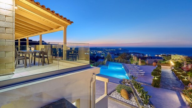 Una terrazza panoramica sul tetto con piscina, posti a sedere all'aperto e vista sul mare.