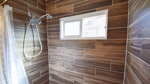 A shower with a rain showerhead, a window, and a curtain.