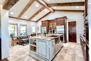 A kitchen with a large island, wooden cabinets, and a stone floor.