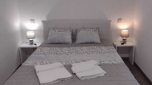 Ett litet hotellrum med en säng, två sänglampor och ett litet bord med en lampa.