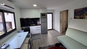 Ett kompakt bostadsutrymme med ett litet kök, en matplats och en sittgrupp.