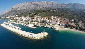 A coastal town with a marina, buildings, and mountains in the background. - Apartments Antonio - Studio with Balcony 2 (Tucepi)