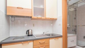 A compact kitchen with a sink, kettle, and wooden cabinets. - Apartments Antonio - Studio with Balcony (2+1) - 5 (Tucepi)