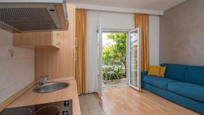 A compact kitchen with a sink, stove, and a sliding glass door leading to a balcony. - Apartments Antonio - One Bedroom Apartment with Balcony - 1 (Tucepi)