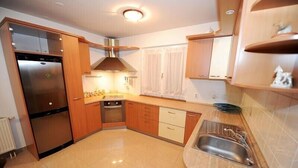 Eine moderne Küche mit Edelstahlgeräten, Holzschränken und einer gefliesten Spritzschutzwand.