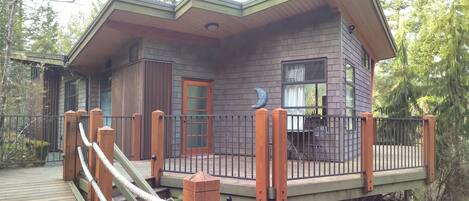 A two-story cabin with a deck and a wooden staircase.