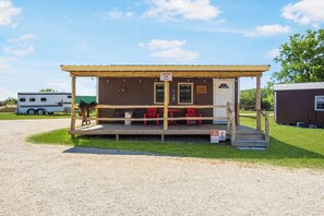 Eine kleine Holzhütte mit Veranda, ein Schild, das das Parken und Haustiere verbietet, und ein Pferd vor der Tür.