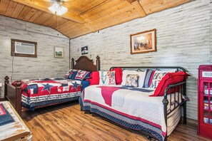 A room with two beds, wooden flooring, a wooden ceiling, and a red telephone booth. - RRR Lonestar - Medina Riverfront | Swim | Fish (Medina)