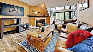 Una sala de estar con chimenea, televisión y un ventanal grande.