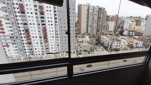 Blick aus einem Fenster auf eine Stadtlandschaft mit Hochhäusern und einer Straße mit Fahrzeugen.