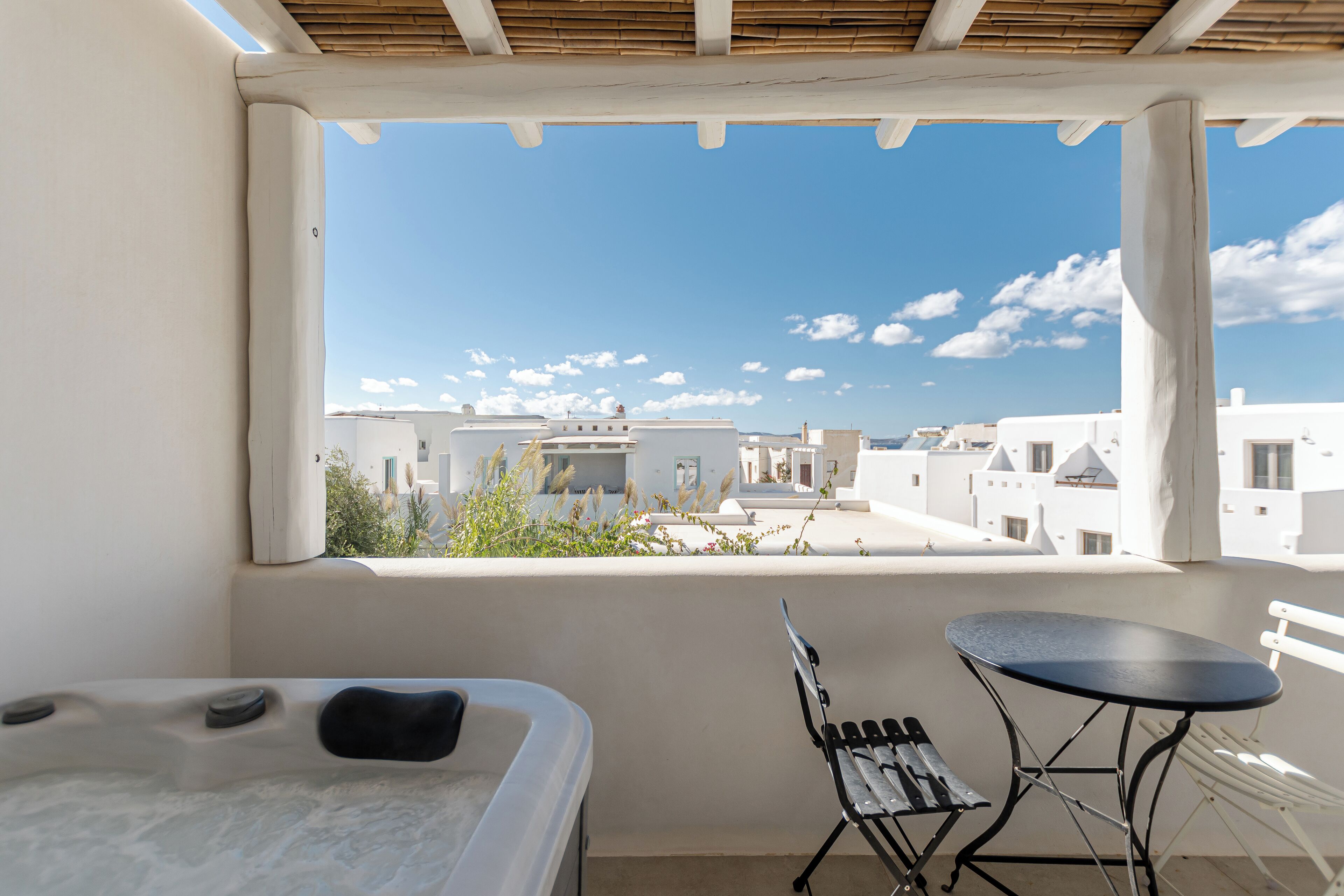 Ein Balkon mit weißer Wand, einem schwarzen Tisch, einer Bank und einem Whirlpool.