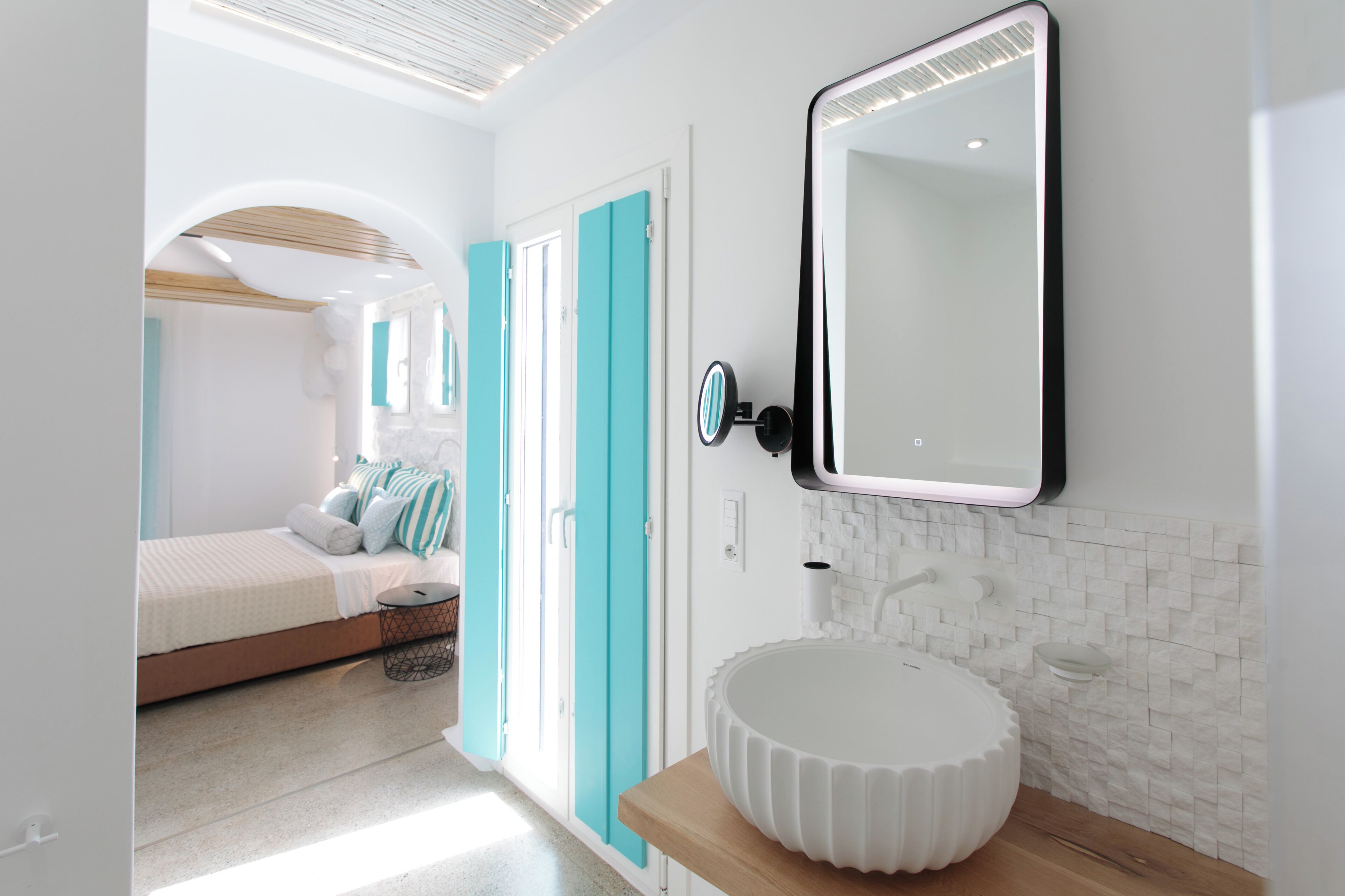 A modern bathroom with a white sink, a mirror, and a wooden countertop.