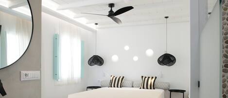 Ein modernes Schlafzimmer mit einem großen Bett, einem Deckenventilator und einem runden Spiegel.
