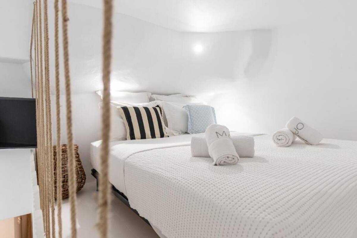 Ein modernes Hotelzimmer mit einem ordentlich bezogenen Bett, weißer Bettwäsche und einigen dekorativen Kissen.