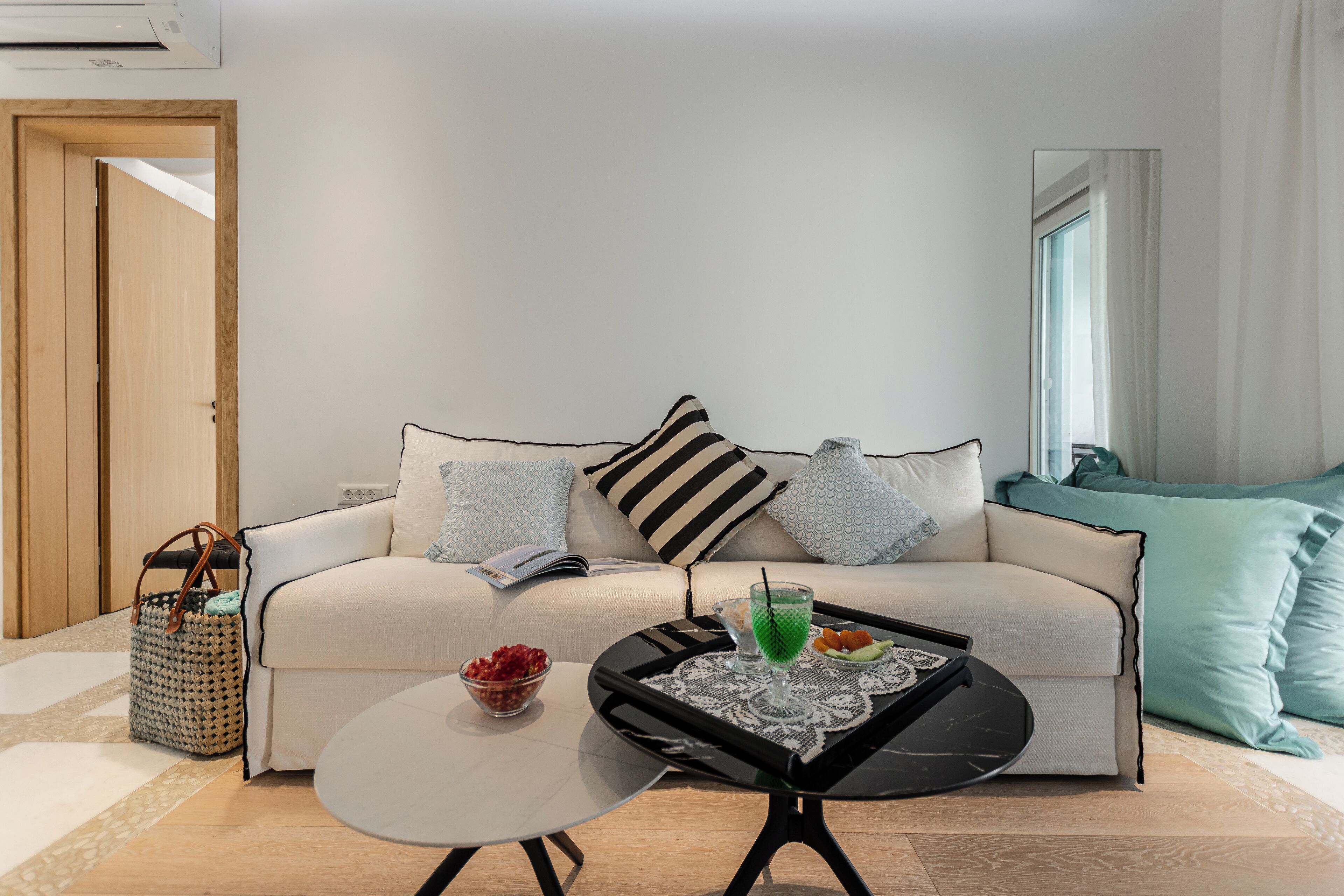 A modern living room with a sofa, a coffee table, and a side table. There is a basket and a bowl on the floor.