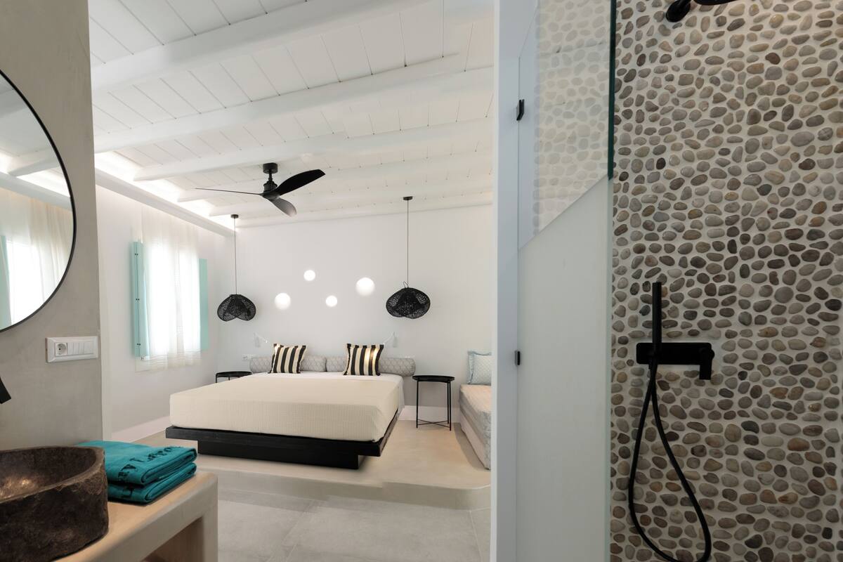 Ein modernes Schlafzimmer mit einem großen Bett, einem Deckenventilator und einer Steinwand.