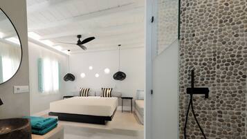 Un dormitorio moderno con una cama grande, un ventilador de techo y una pared de piedra.