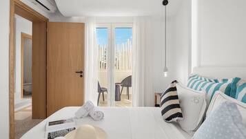 A hotel room with a bed, a bathroom, and a balcony with a view of tall buildings.