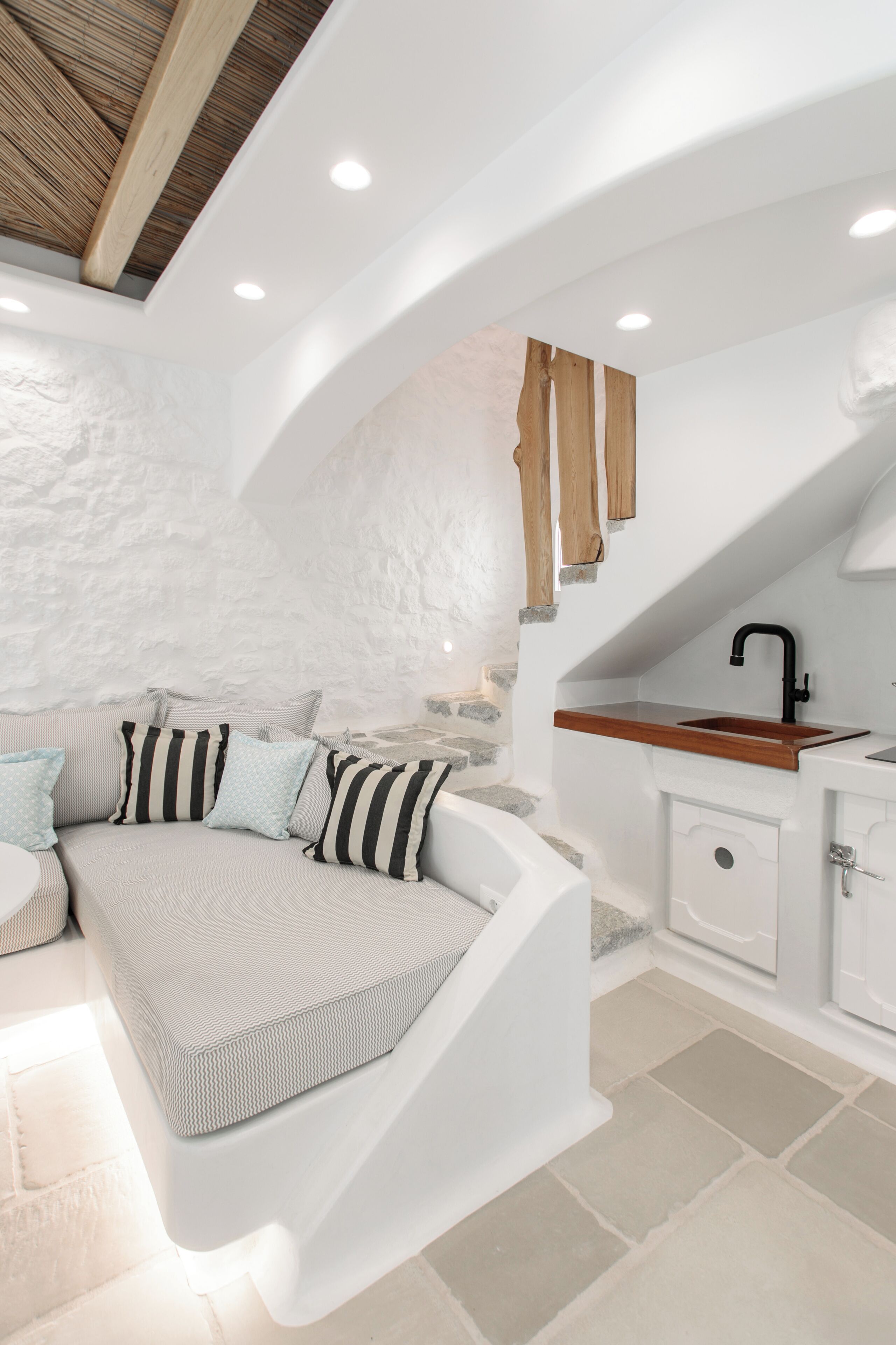 Una cocina moderna con armarios blancos, encimera de madera e instalación de lavamanos.