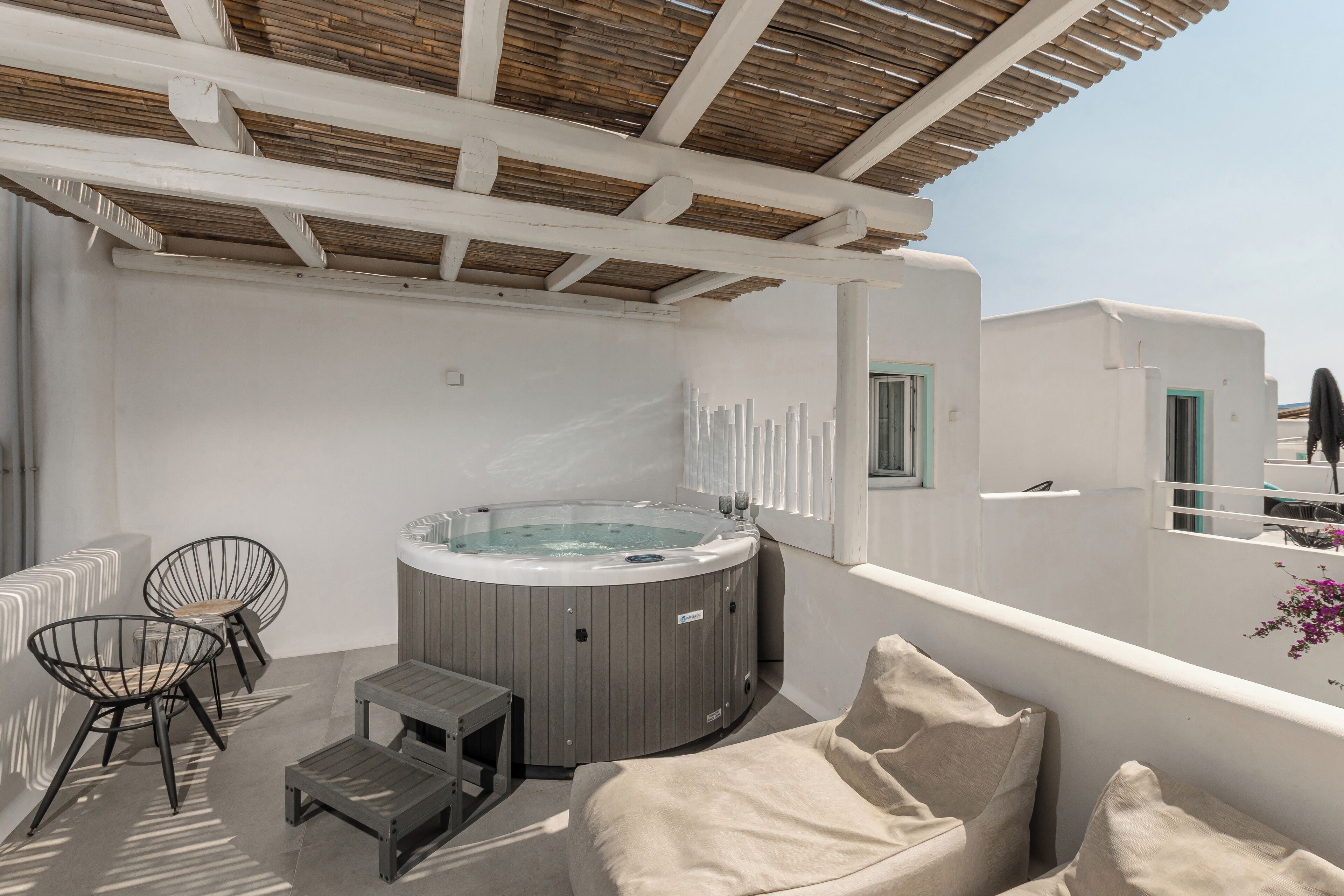 A rooftop terrace with a hot tub, seating area, and a view of the city.