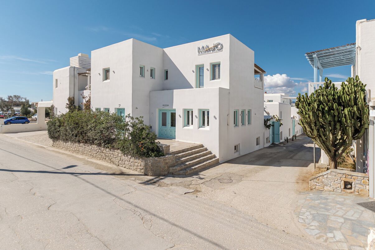 Un edificio blanco con puerta y ventanas azules, con el letrero "MAJO".
