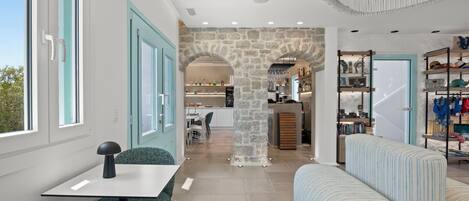 Un interior moderno con un arco de piedra, una zona de comedor con mesa y sillas, y una sala de estar con sofá.