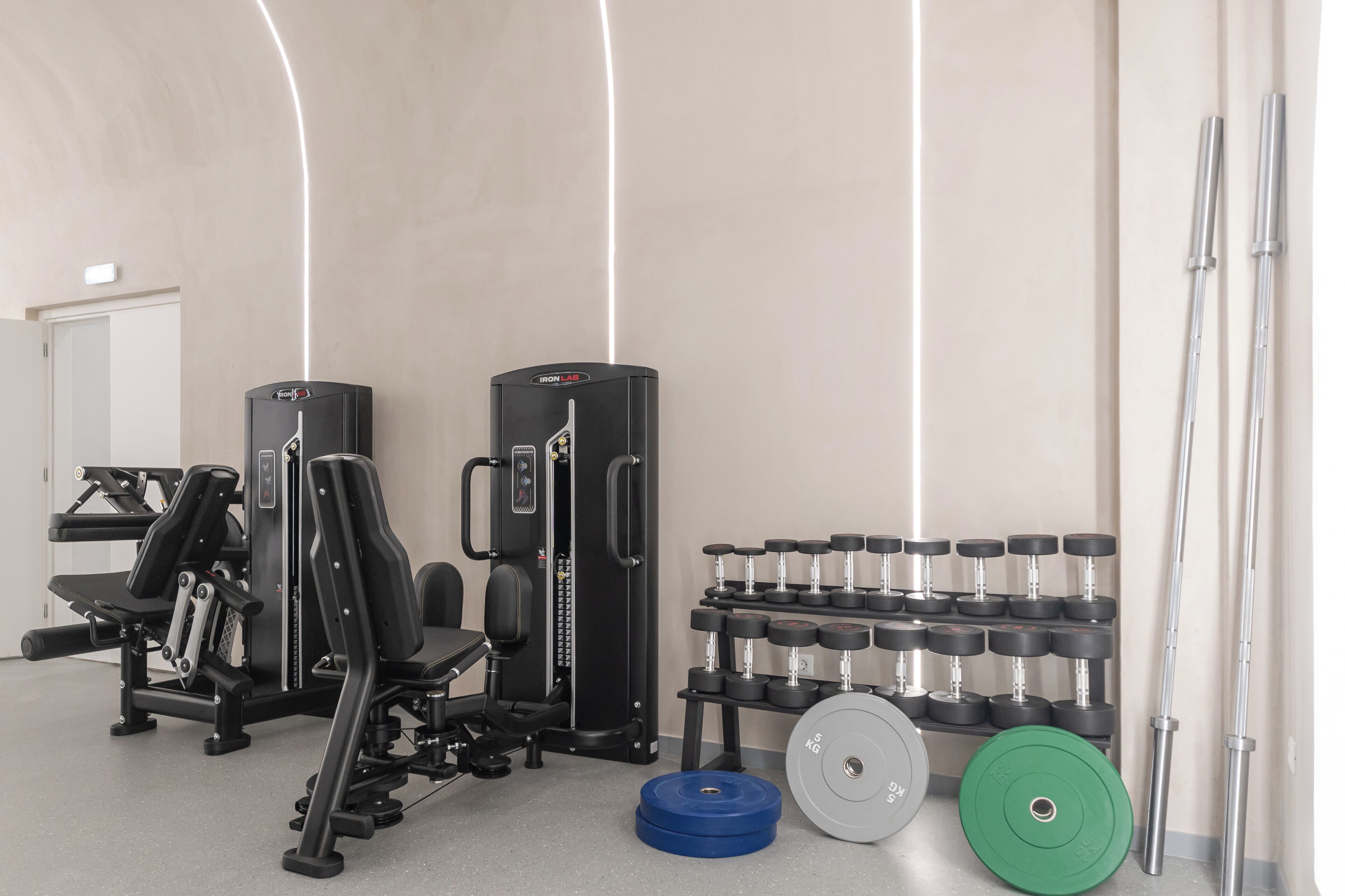 A gym with weightlifting equipment, including dumbbells and barbells.