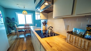 Une cuisine avec des plans de travail en bois, une bouilloire et un panier rempli d’en-cas.