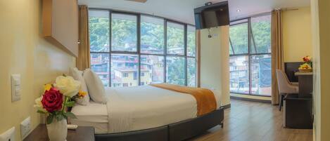 Quarto de hotel moderno com uma cama grande, uma escrivaninha e uma televisão.