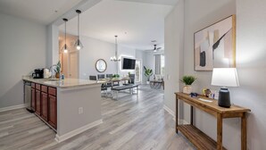 A modern kitchen with a central island, wooden cabinets, and pendant lighting.