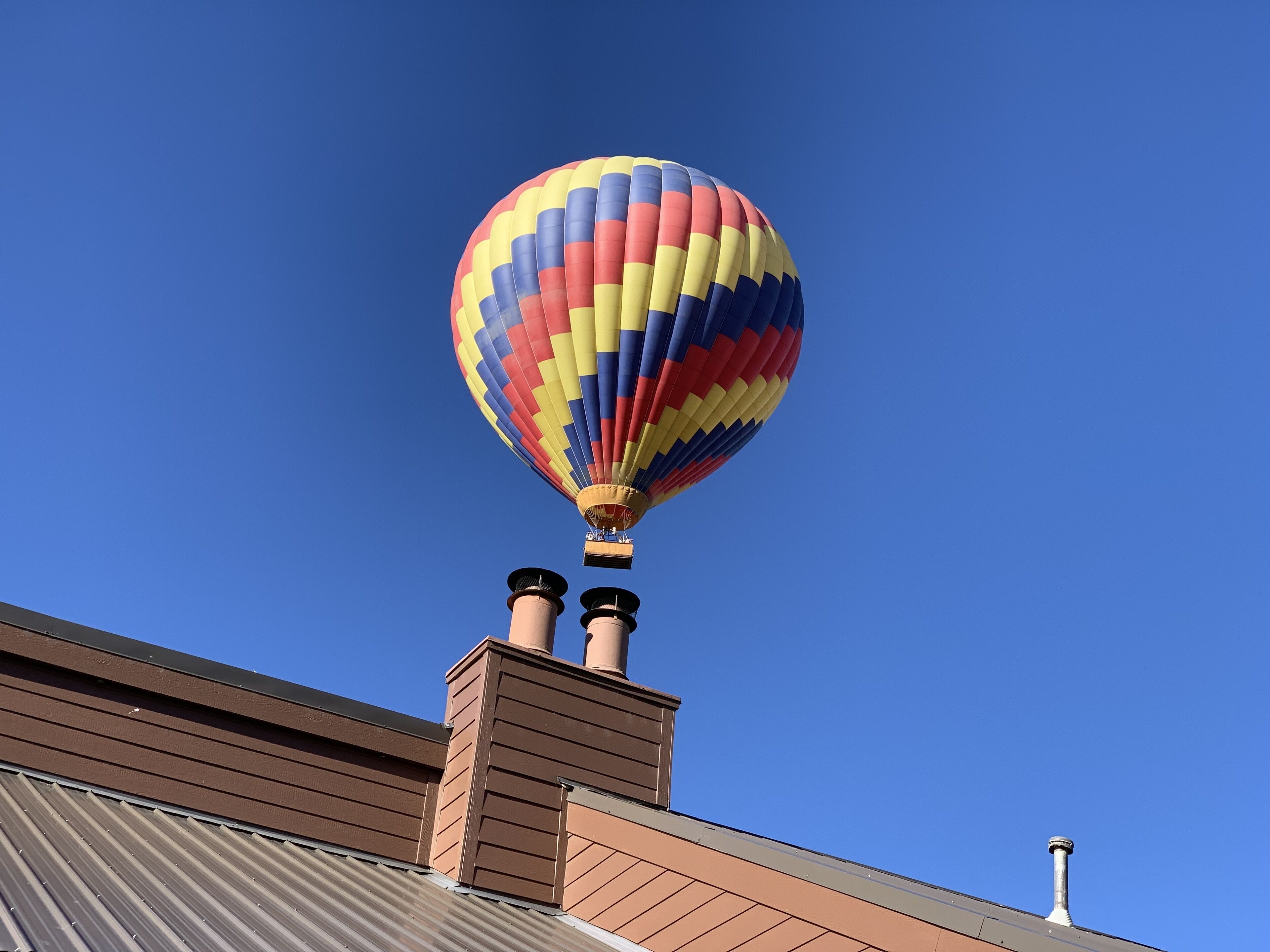 Een luchtballon met een streepjespatroon, vastgemaakt aan het dak van een gebouw.