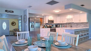 A modern kitchen with white cabinets, a stainless steel refrigerator, and a built-in microwave. - Pine Island Beach House!  *Gulf Access, Heated Pool, Hot Tub & Boat Dock* (St. James City)