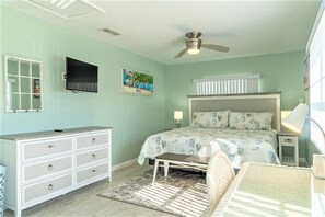 Ein Schlafzimmer mit Bett, Kommode, Fernseher und Deckenventilator.