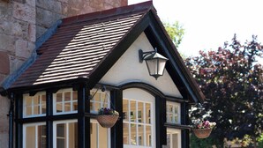 A traditional building with a white facade, black trim, and a tiled roof. There are two large windows with white frames and a door with a black frame. - A unique, spectacular detached home in a much sought-after area with unbeatable panoramic sea views. (North Berwick)