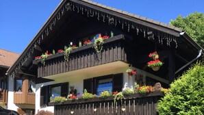 A two-story chalet with a wooden balcony adorned with hanging plants and flowers. - NEW 5 star holiday comfort apartment (Braunlage)