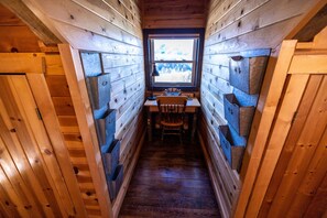 A narrow wooden cabin with a window, a table, and chairs.