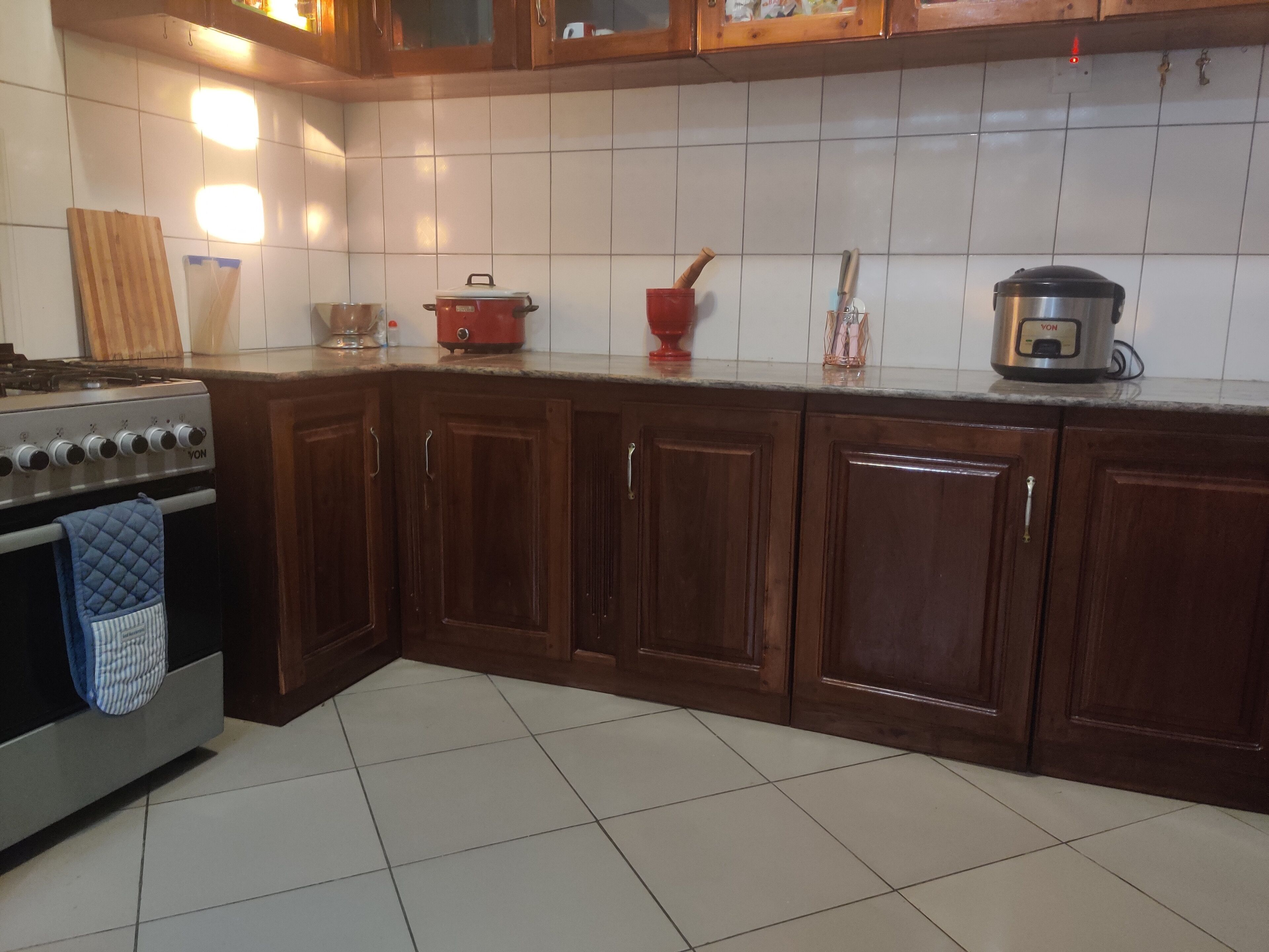 Een keuken met houten kastjes, een fornuis en diverse keukengerei.