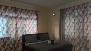 Ein Schlafzimmer mit Bett, Vorhängen, Deckenventilator und Nachttisch.
