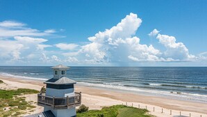 A lighthouse on a beach with a clear sky and ocean.
