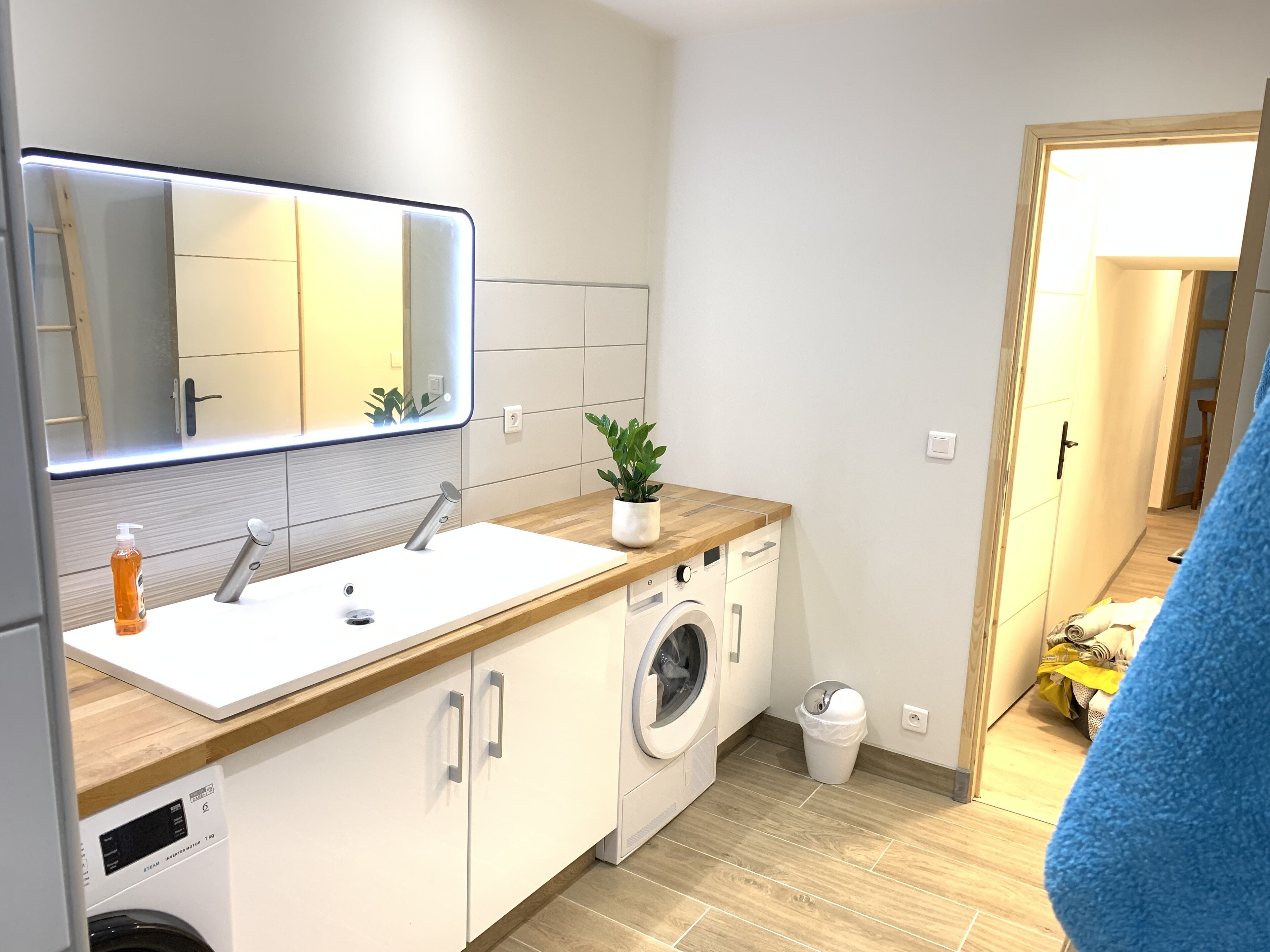 A modern kitchen with a built-in washing machine, a sink, and a mirror above it.