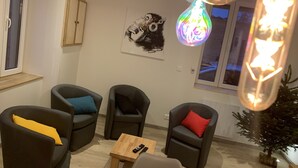 A modern living room with three dark armchairs, a small wooden coffee table, and a wall-mounted abstract painting. - Gîte Le BISTANCLAC in the heart of the town of CHARLIEU. (Charlieu)